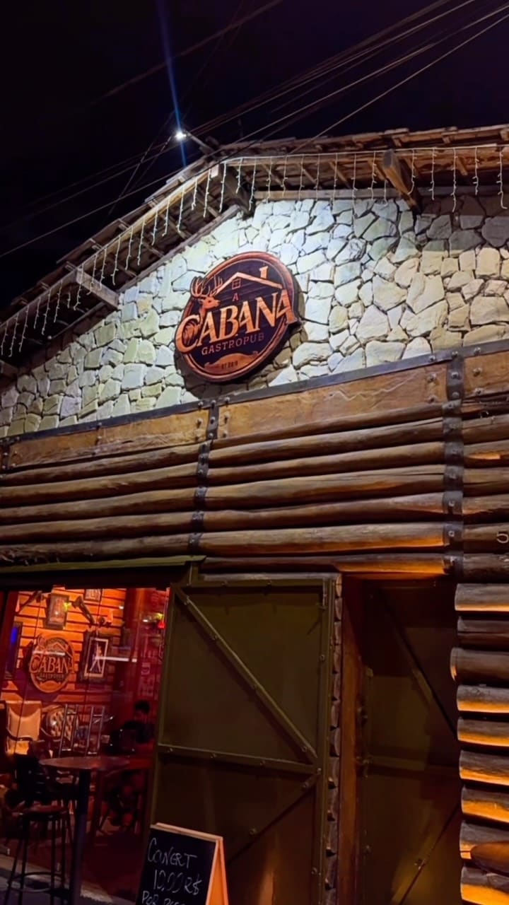 Fachada de pedra e troncos da Cabana